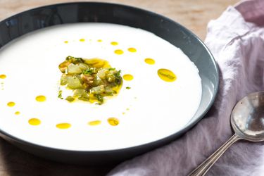 A bowl of ajo blanco garnished with green grapes, mint, and a drizzling of olive oil. 