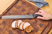 Sliced meat next to the Victorinox Fibrox Pro 12-Inch Slicing Knife with Granton Blade