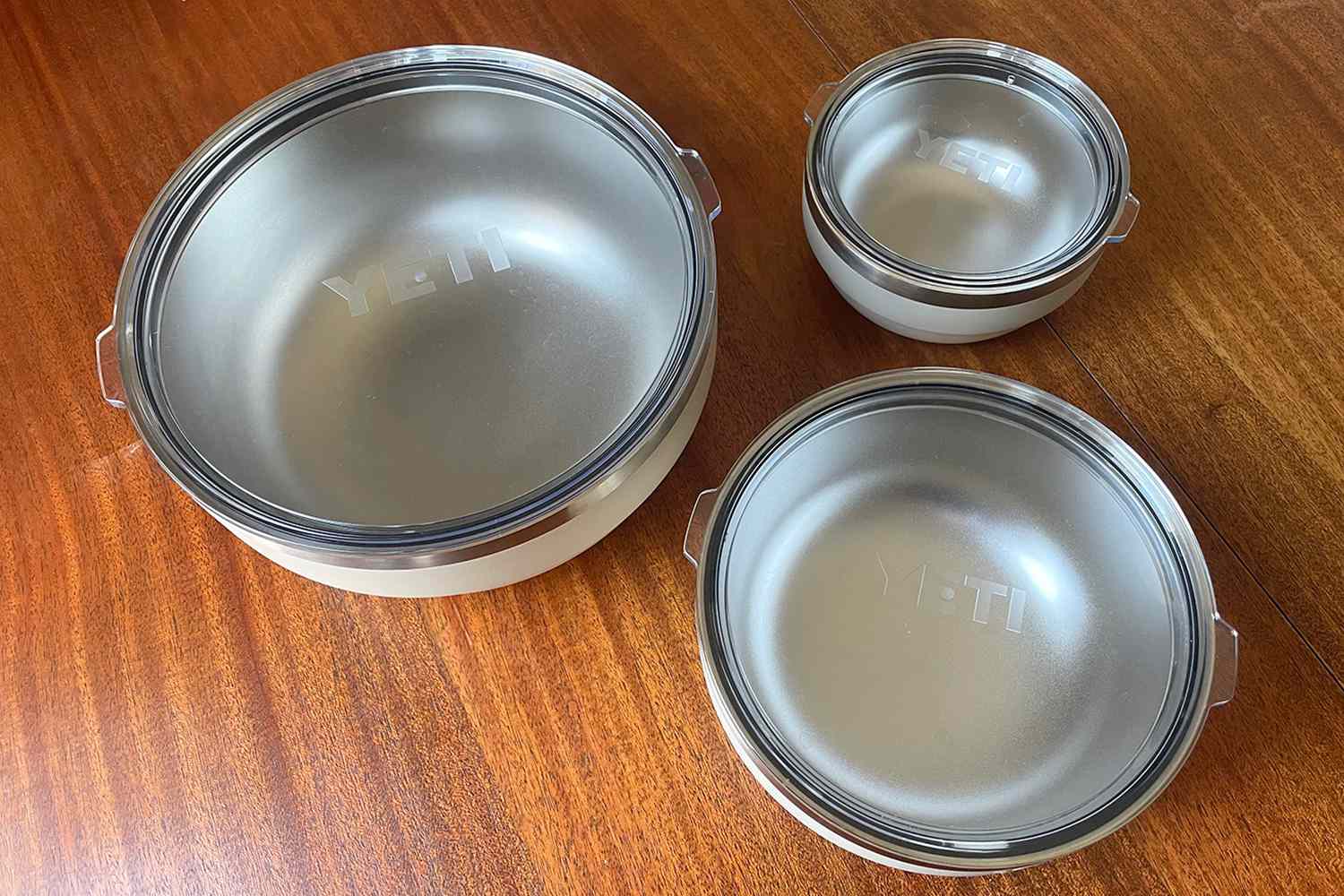 Three Yeti Rambler bowls of different sizes displayed on a wooden surface