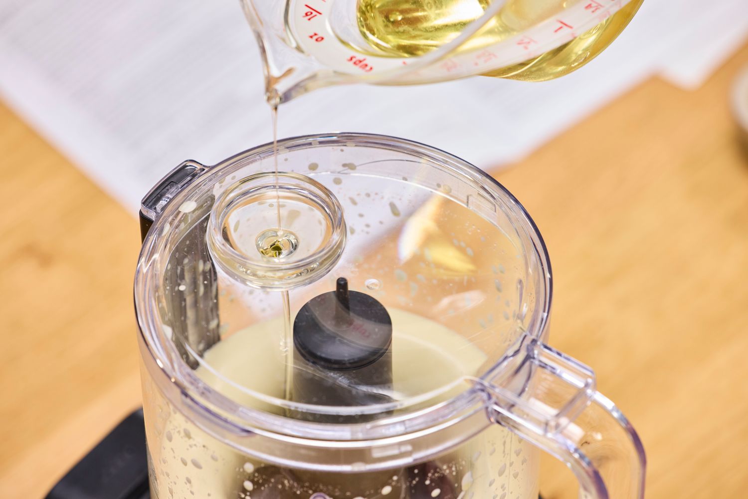 A person pours oil into the KitchenAid Go Cordless 5-Cup Food Chopper