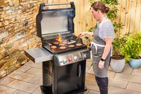 A person cooks meat in the Weber Spirit EX-325s Smart Grill