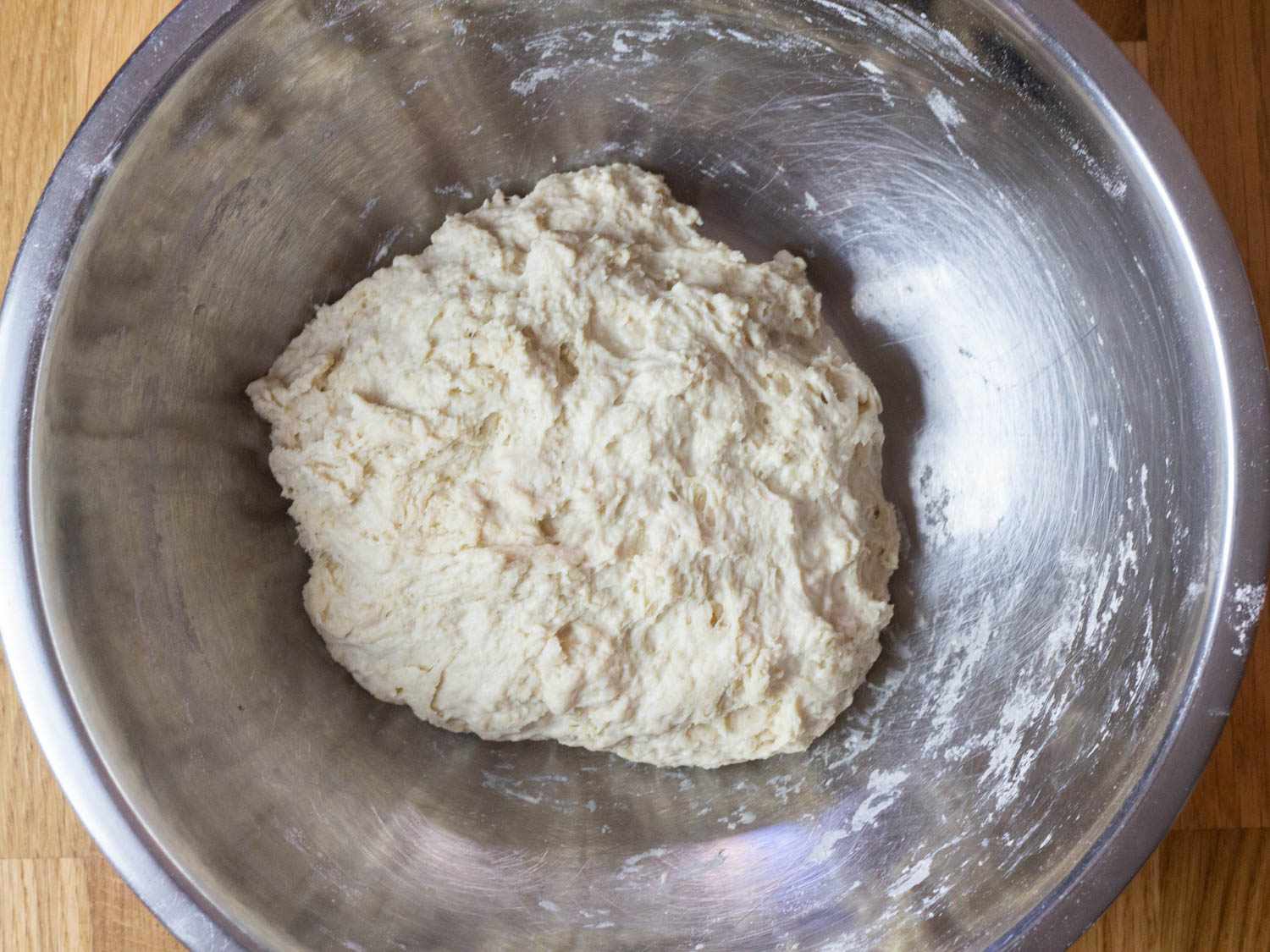 A flour-and-water dough sits in a metal mixing bowl before the levain is mixed in.