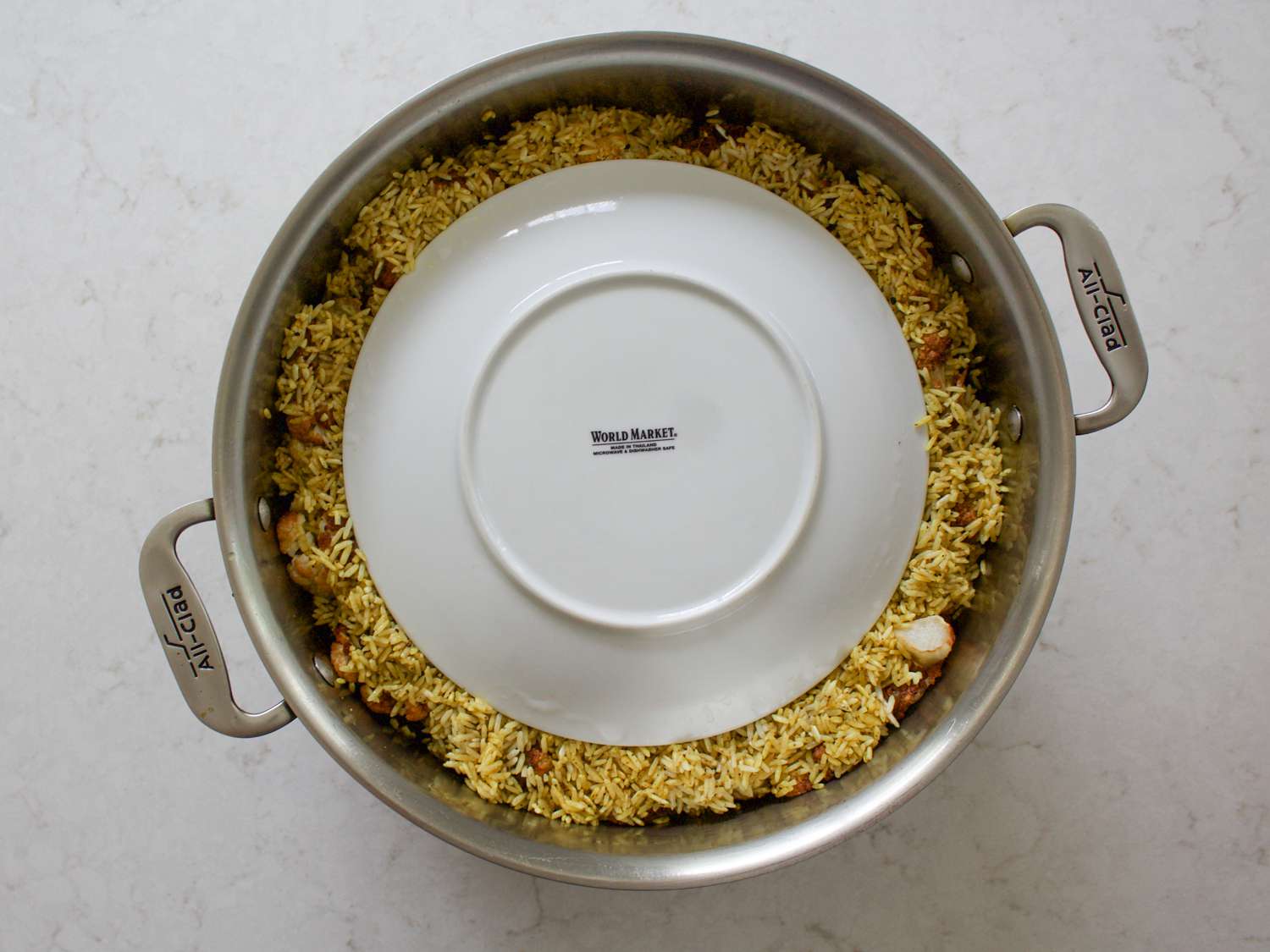 A plate weighing down the maqlubeh in a pot