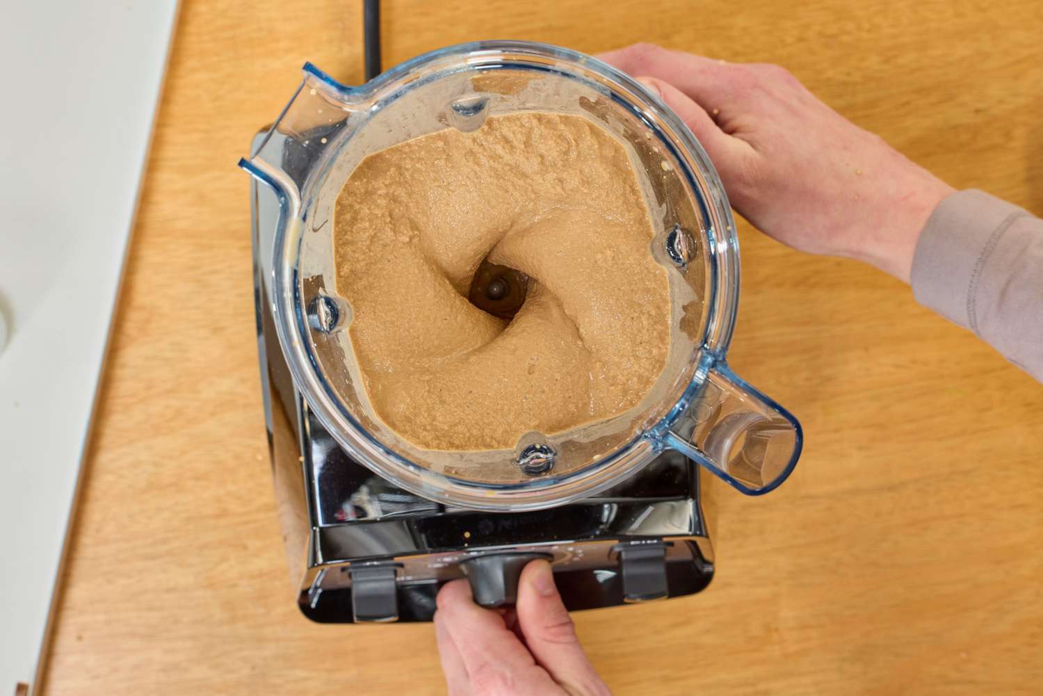 An over head view of two hands touching a lidless Vitamix Propel 510