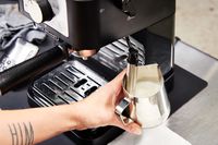 Hand steaming milk using the milk frother of the De'Longhi Stilosa Espresso Machine