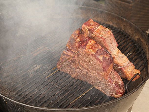 Porterhouses on the grill, which is now emanating a lot of smoke. The surface of the steak is turning mahogany.