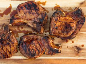 Overhead view of adobo-marinated grilled pork chops, resting on a cutting board.
