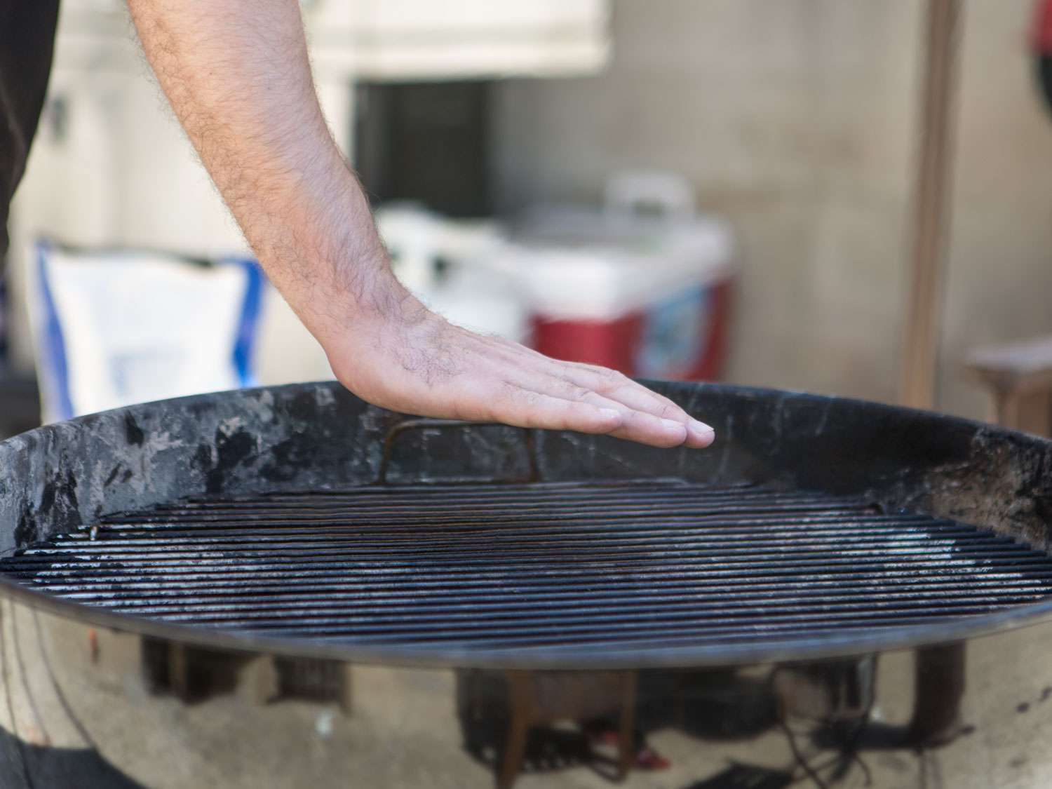 Holding a hand over a hot grill to gauge heat.