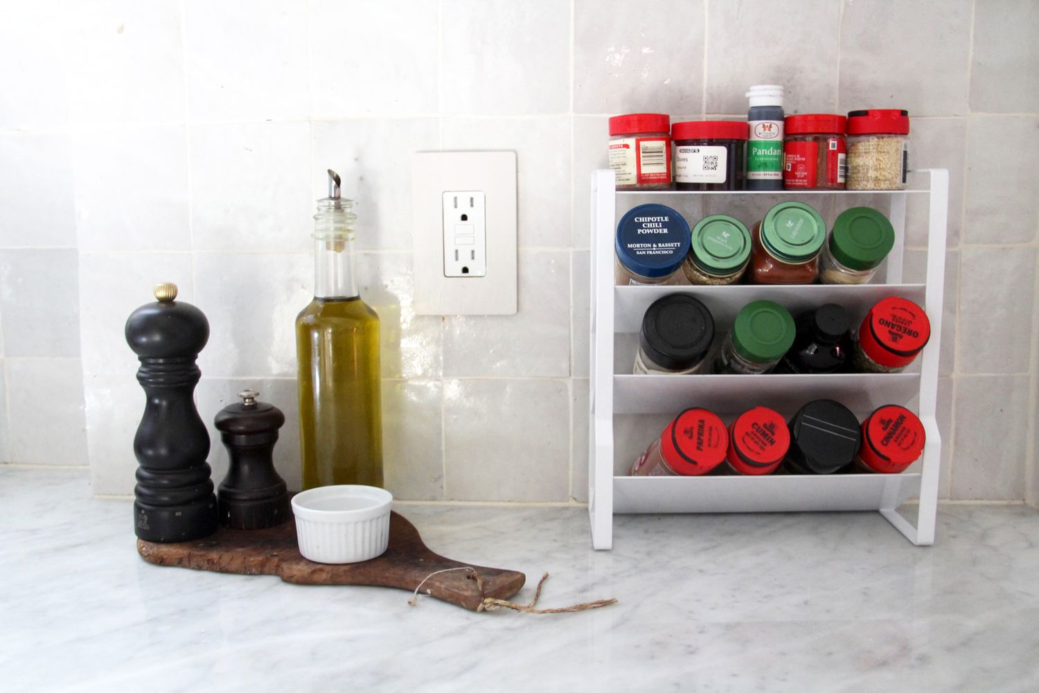A white metal spice rack filled with spices on a kitchen counter