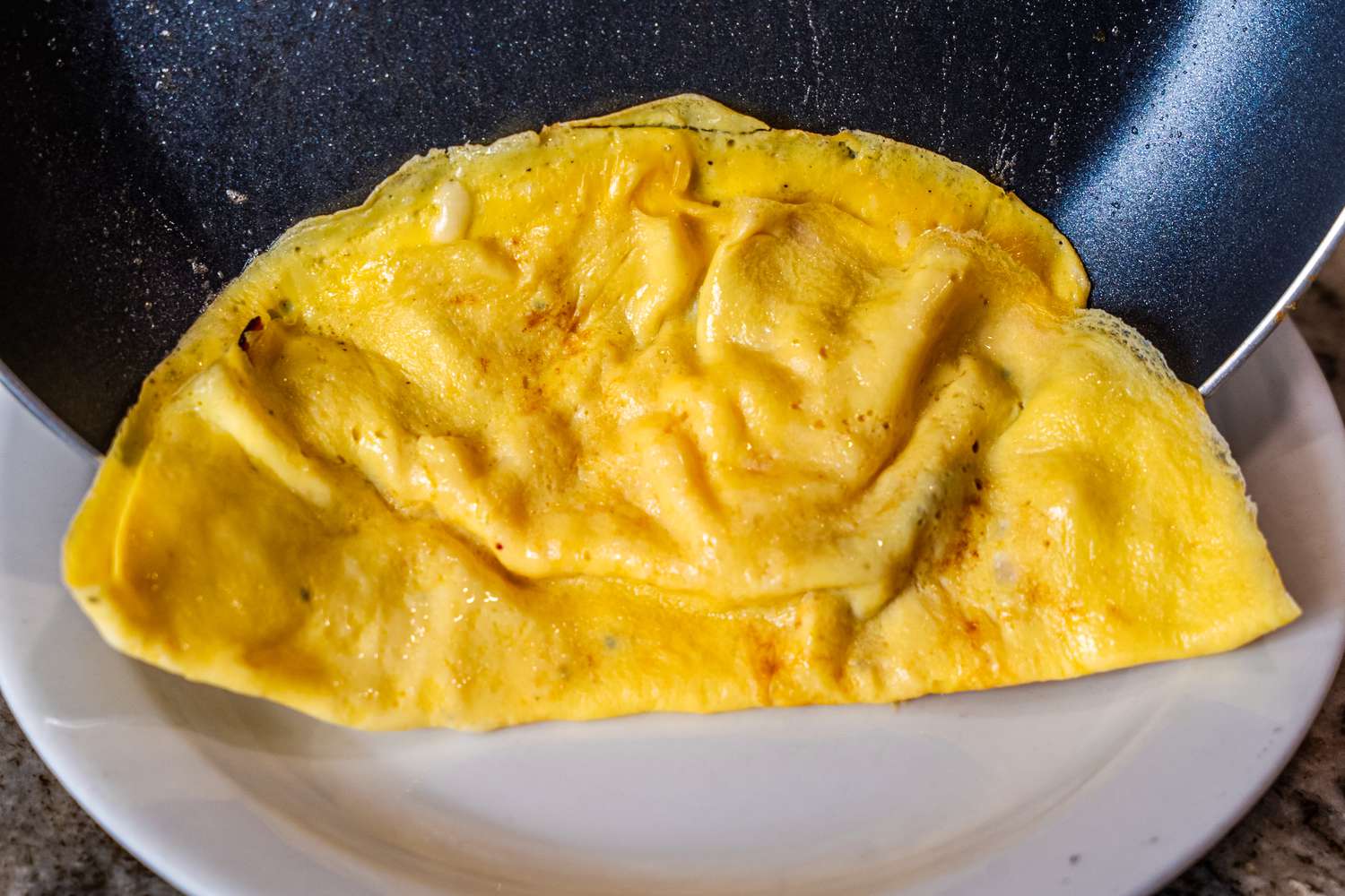 An egg omelet being transferred from the Utopia nonstick pan to a plate