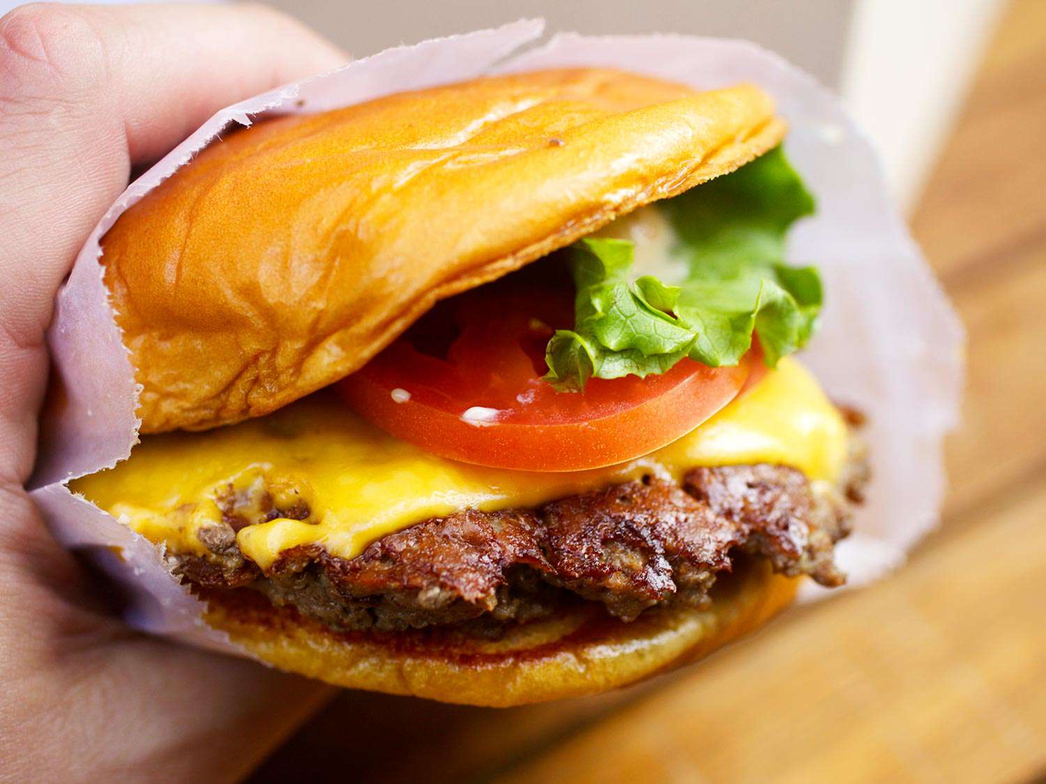 A Shake Shack cheeseburger wrapped in deli paper 