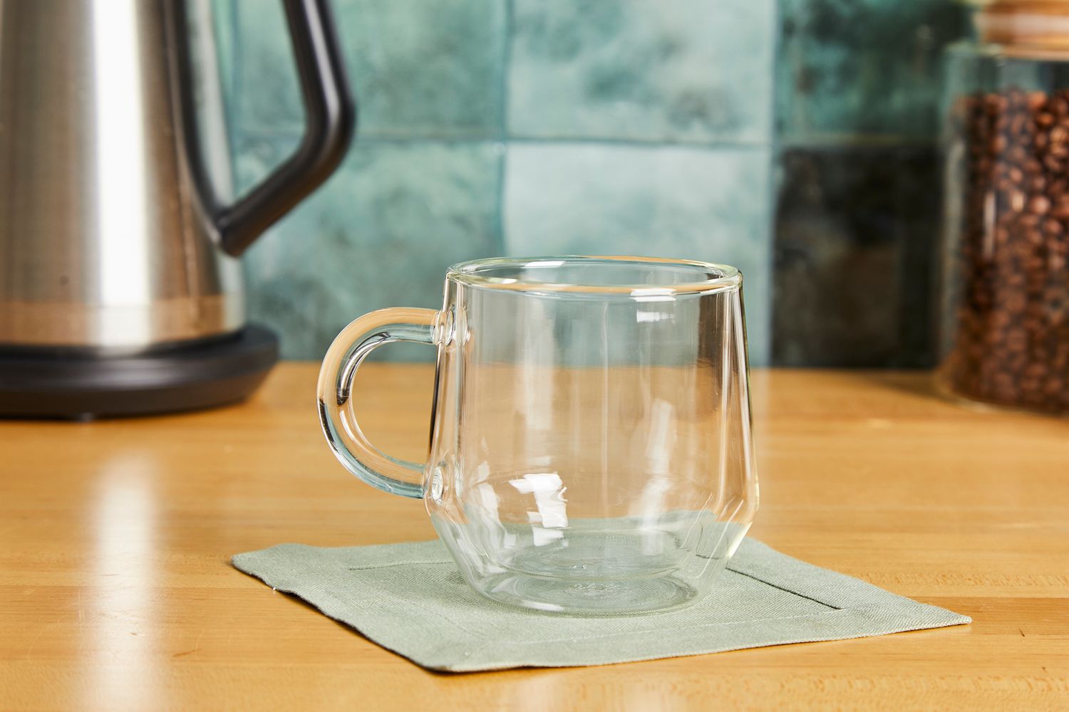 A double walled glass coffee mug on a kitchen countertop.