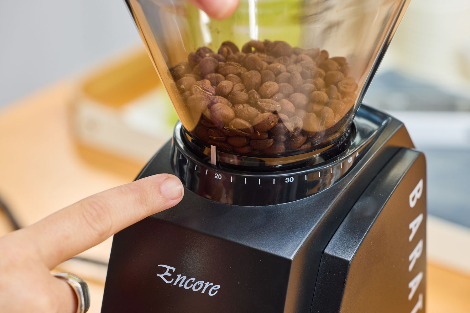 A person points to the grind setting on the Baratza Encore Conical Burr Coffee Grinder