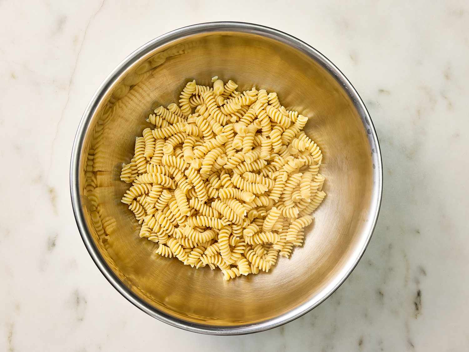 Macaroni in a bowl on a white surface