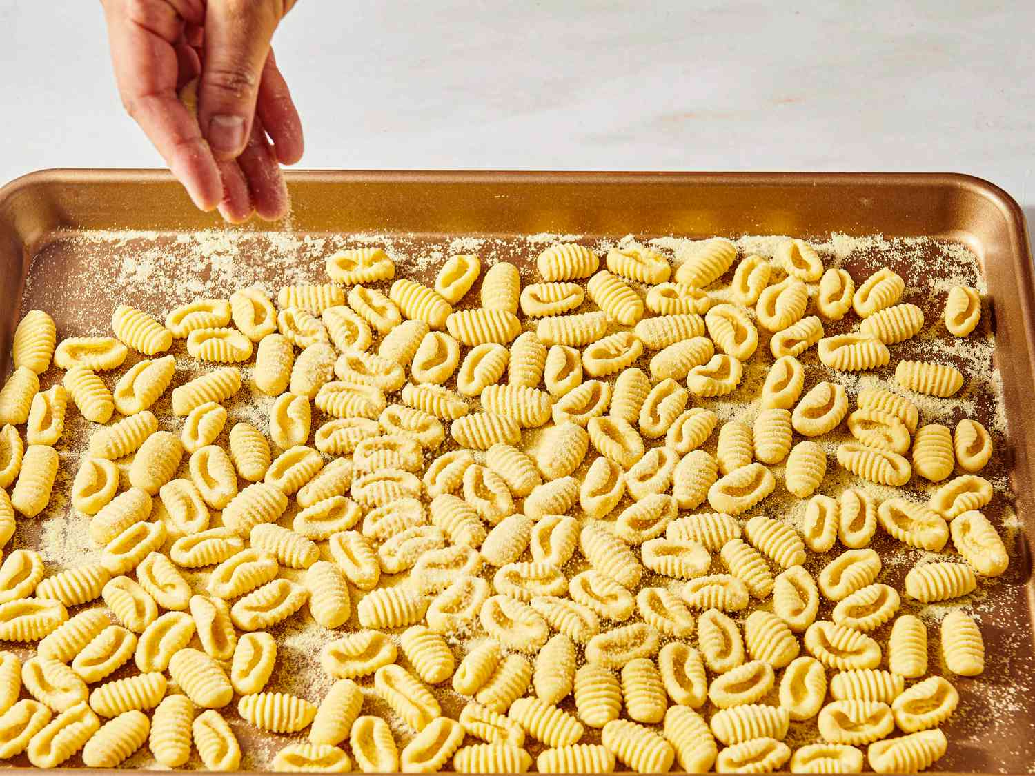 Sprinkling noodles on a baking sheet with semolina