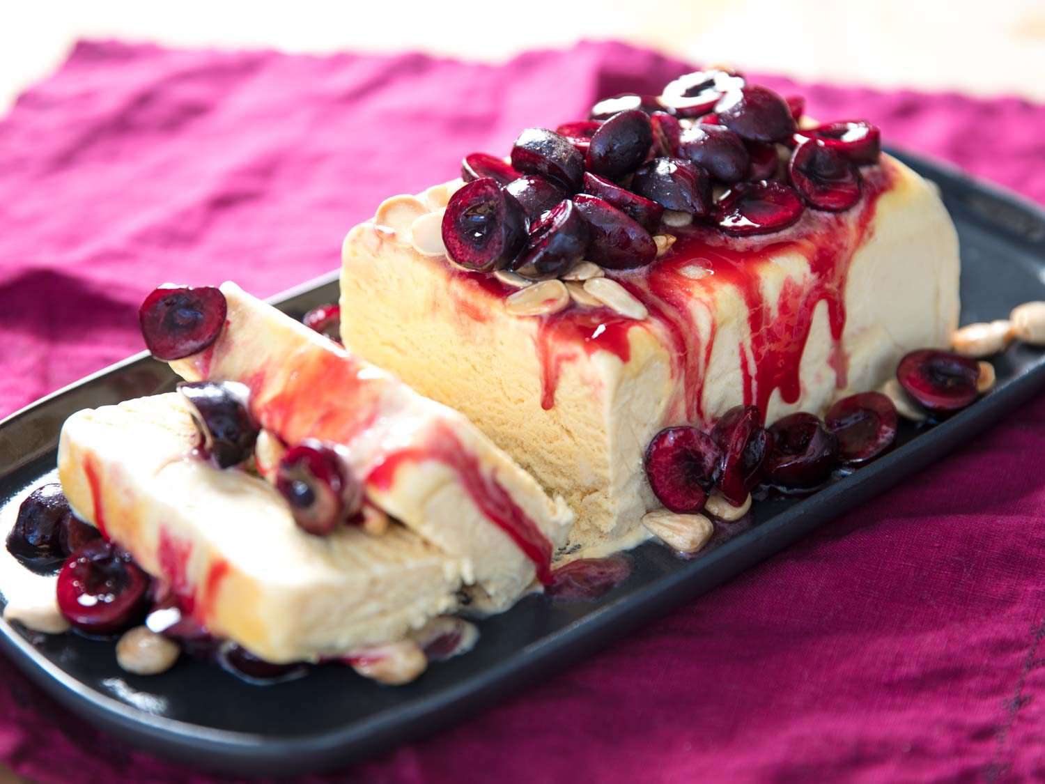 Sliced semifreddo with almonds and macerated cherries on a platter.