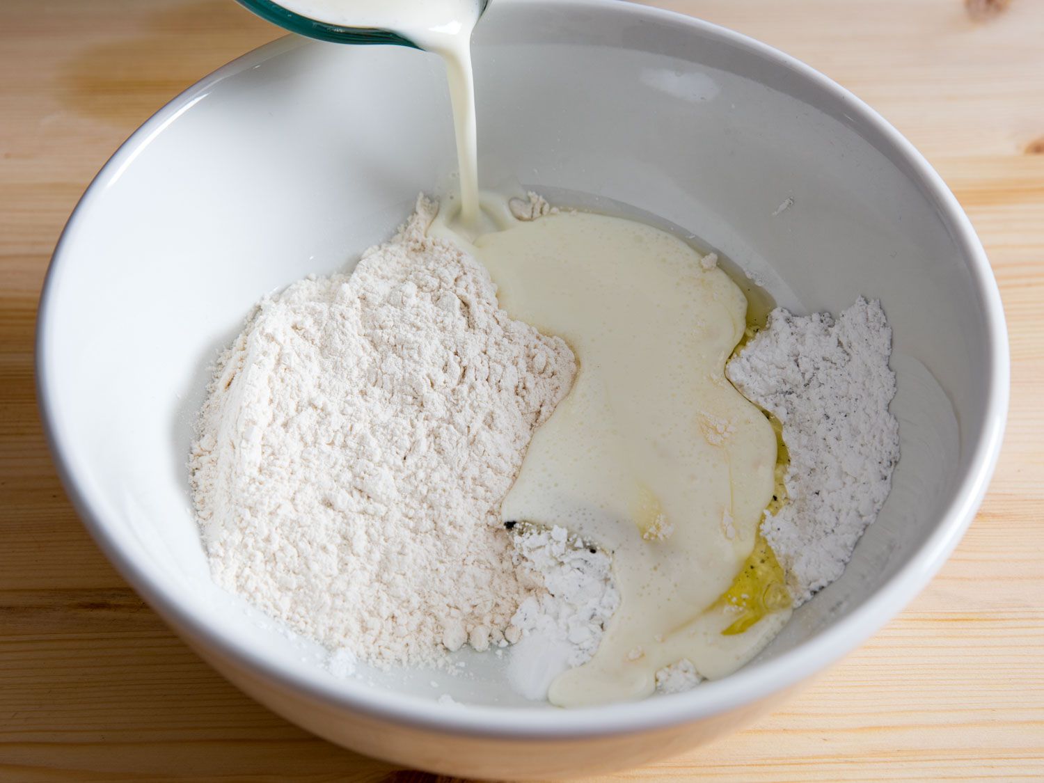 Adding buttermilk to flour to make waffle batter. 