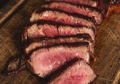 Slices of cooked steak arranged on a wooden surface