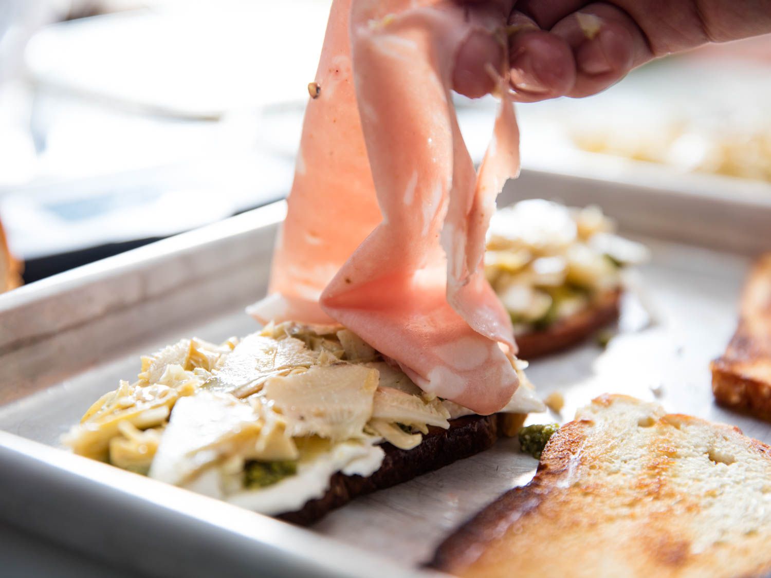 A large, thin slice of mortadella is draped over the rest of the sandwich fillings.