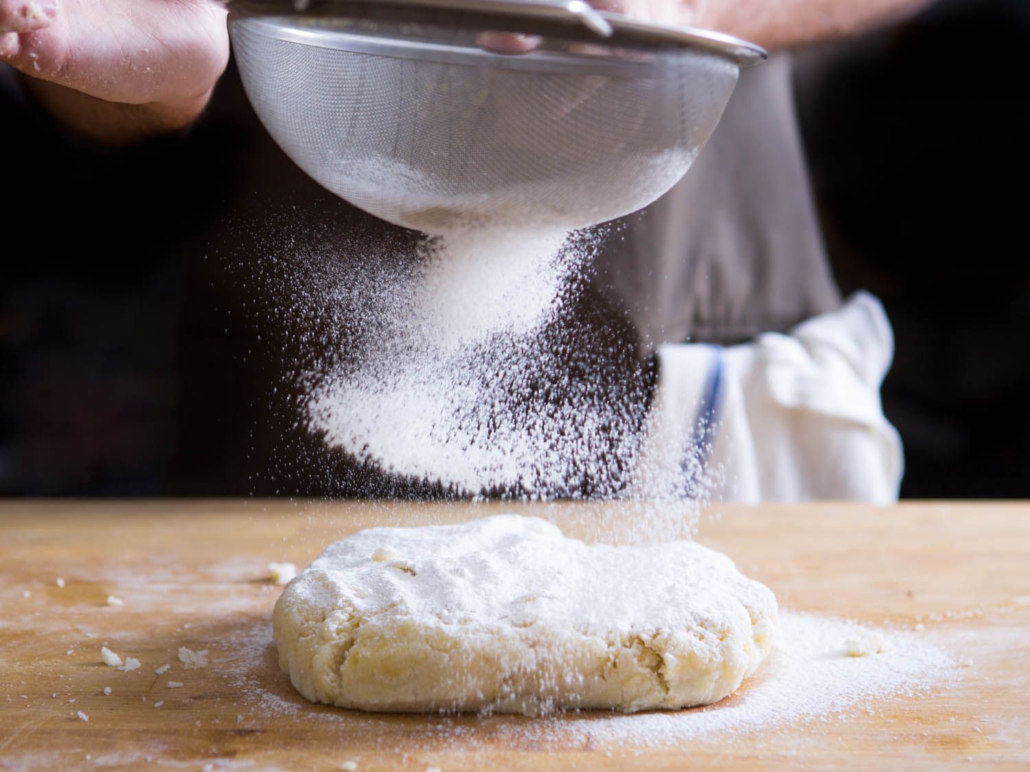 sifting flour onto a piece of dough