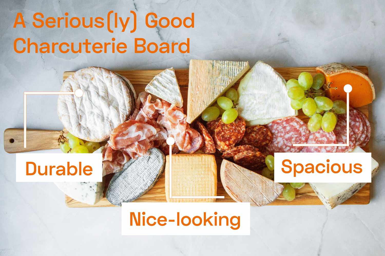 A charcuterie board loaded with meats and cheeses and fruit on a marble surface.