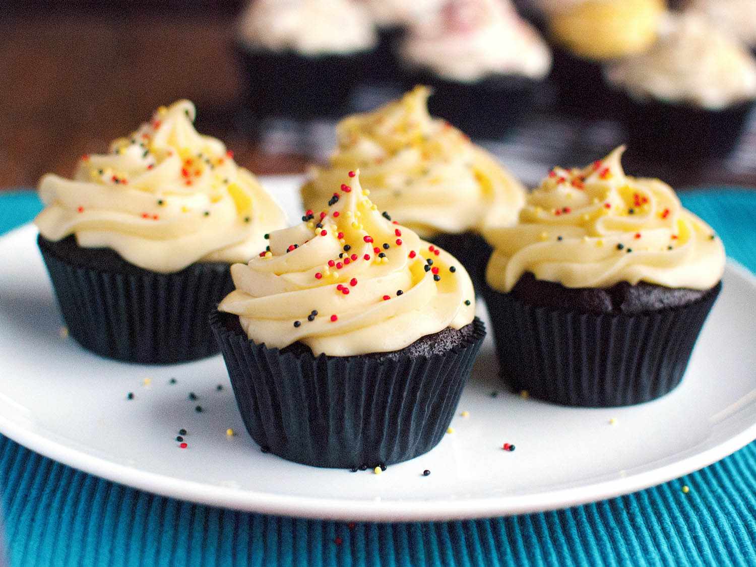 Four German buttercream cupcakes on a plate with sprinkles.