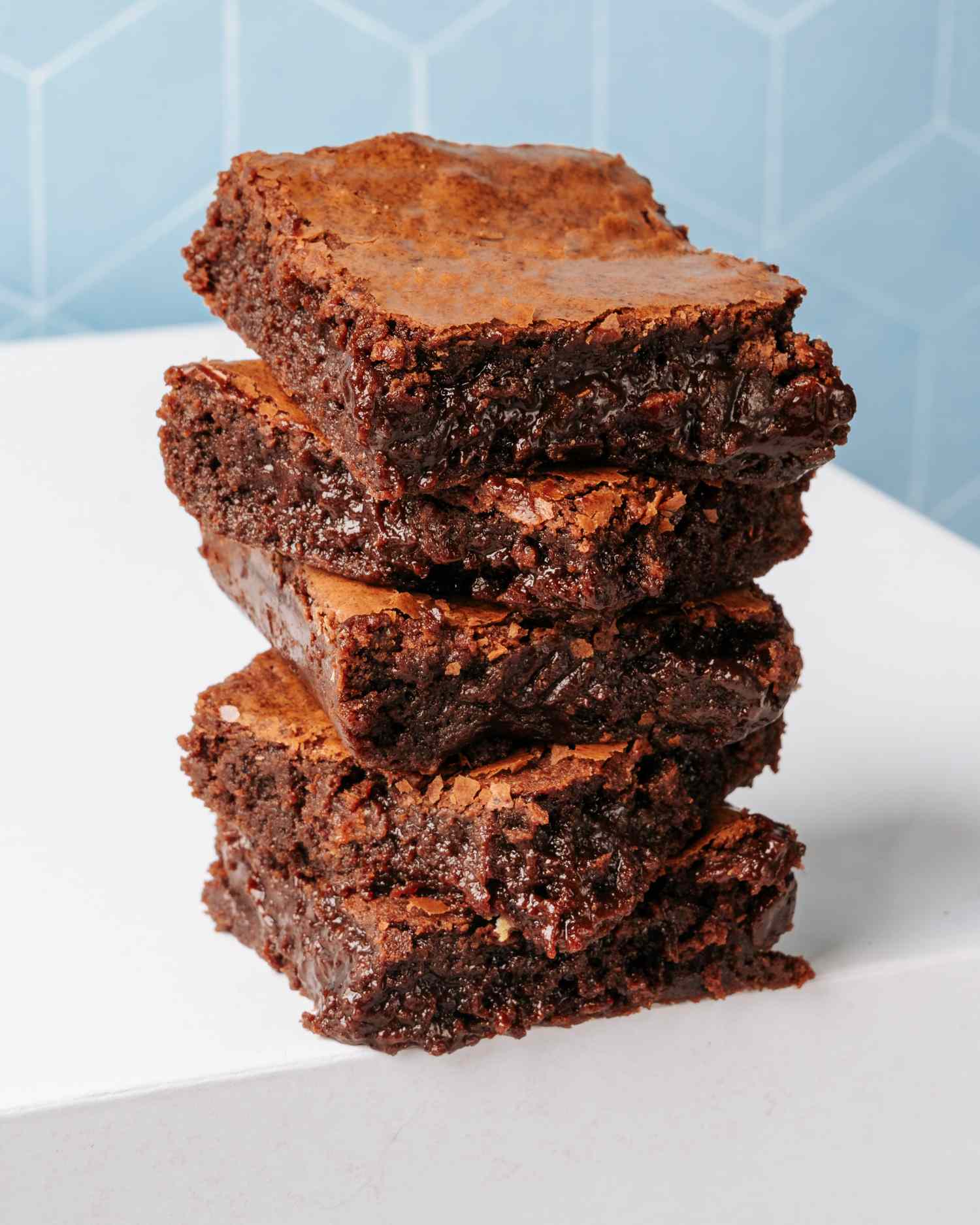 Stack of four brownies on a white surface with a blue tile background