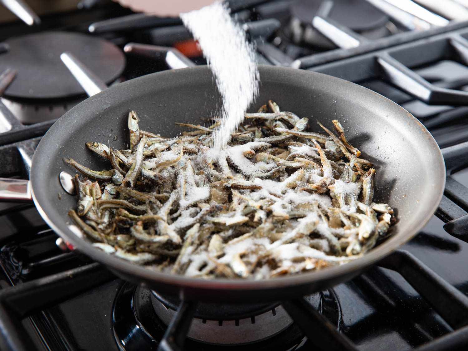 Sugar is added to the pan of anchovies.