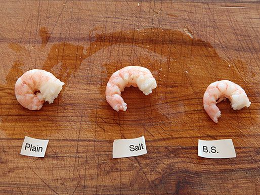Three shrimp lying on a cutting board: one soaked with plain water, one with salted water, and one with baking soda-spiked water. 