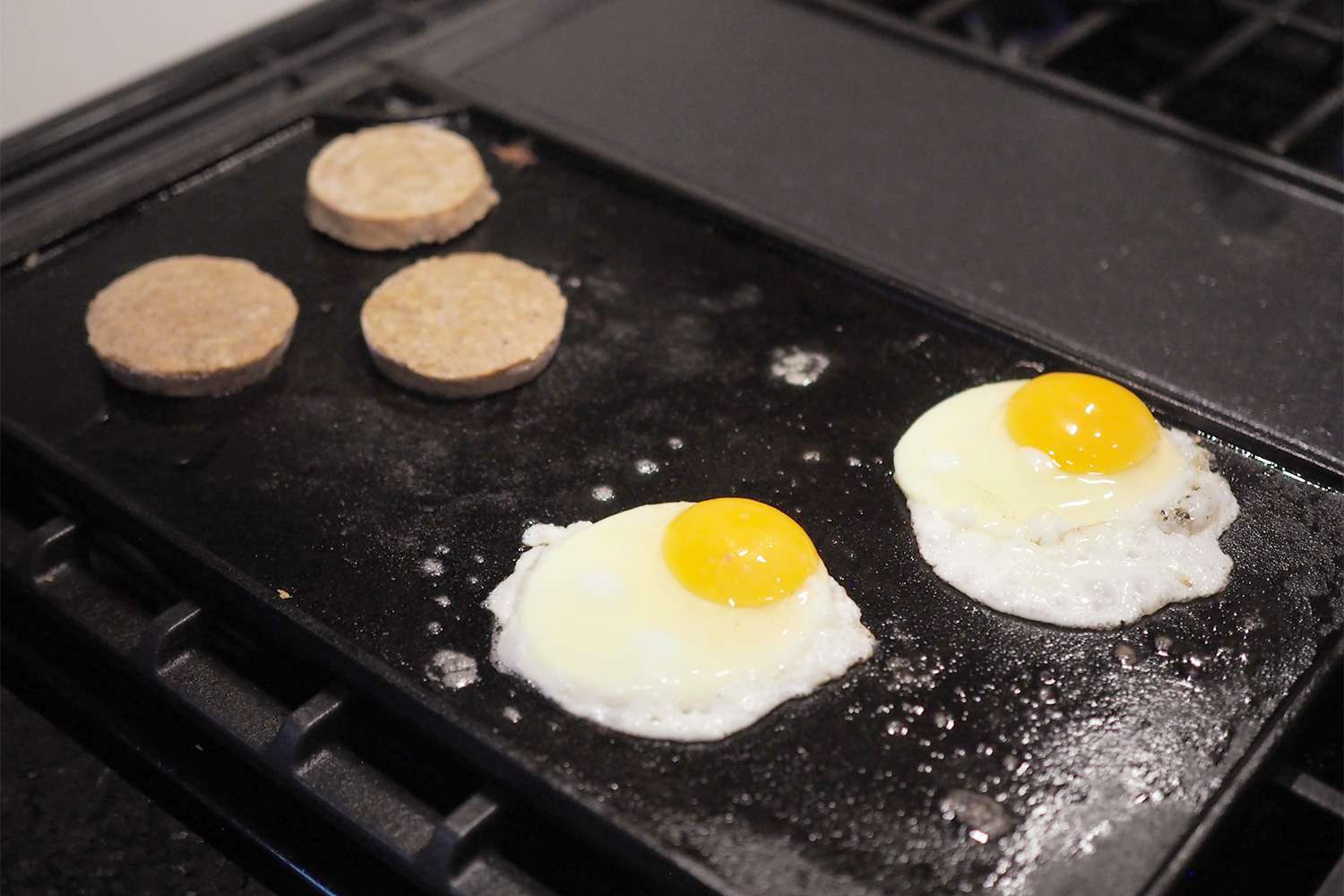 Lodge Reversible griddle on stove with eggs and sausage in low light
