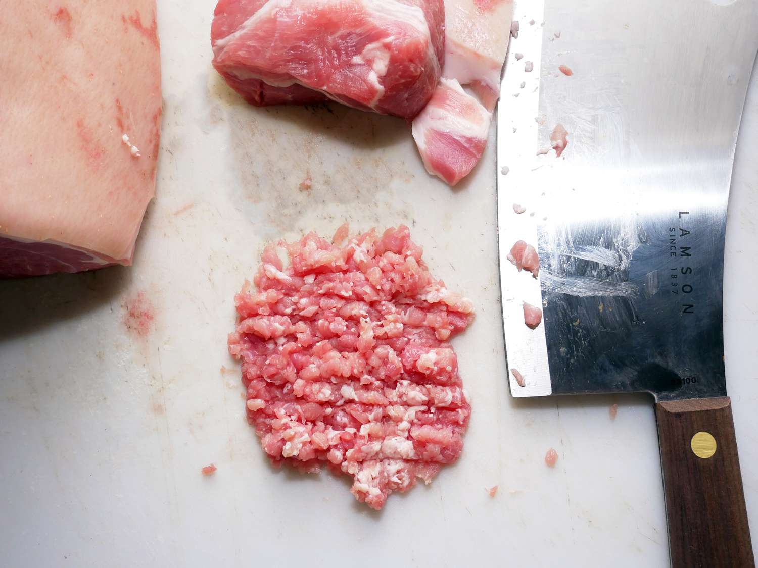 Lamson Meat Cleaver next to a pile of minced pork from a pork shoulder on the side of the cutting board