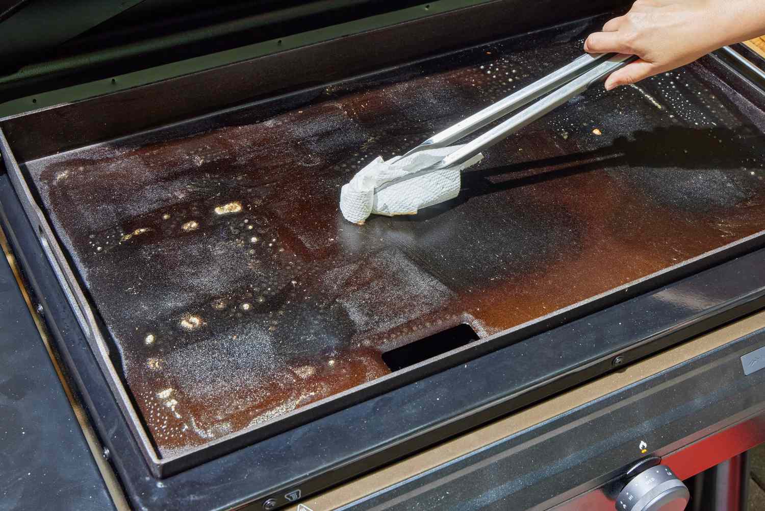 A person cleans the top of the Traeger Flatrock Flat Top Grill