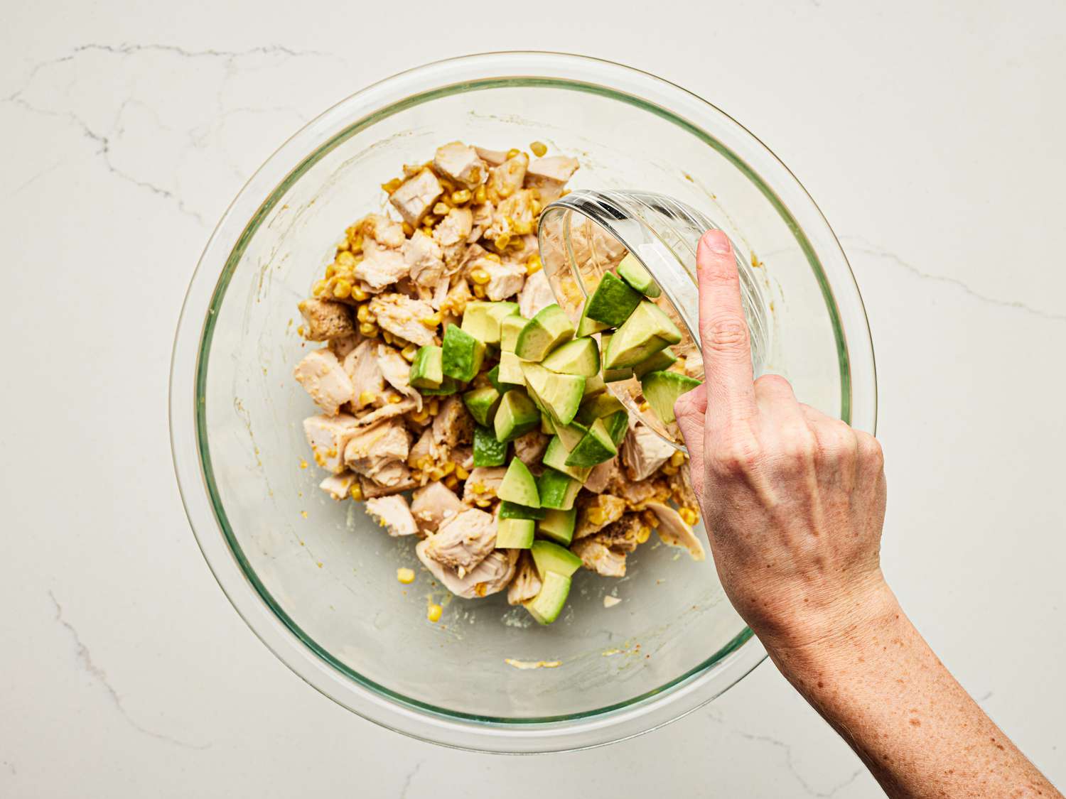 Overhead view of adding avocado to the salad
