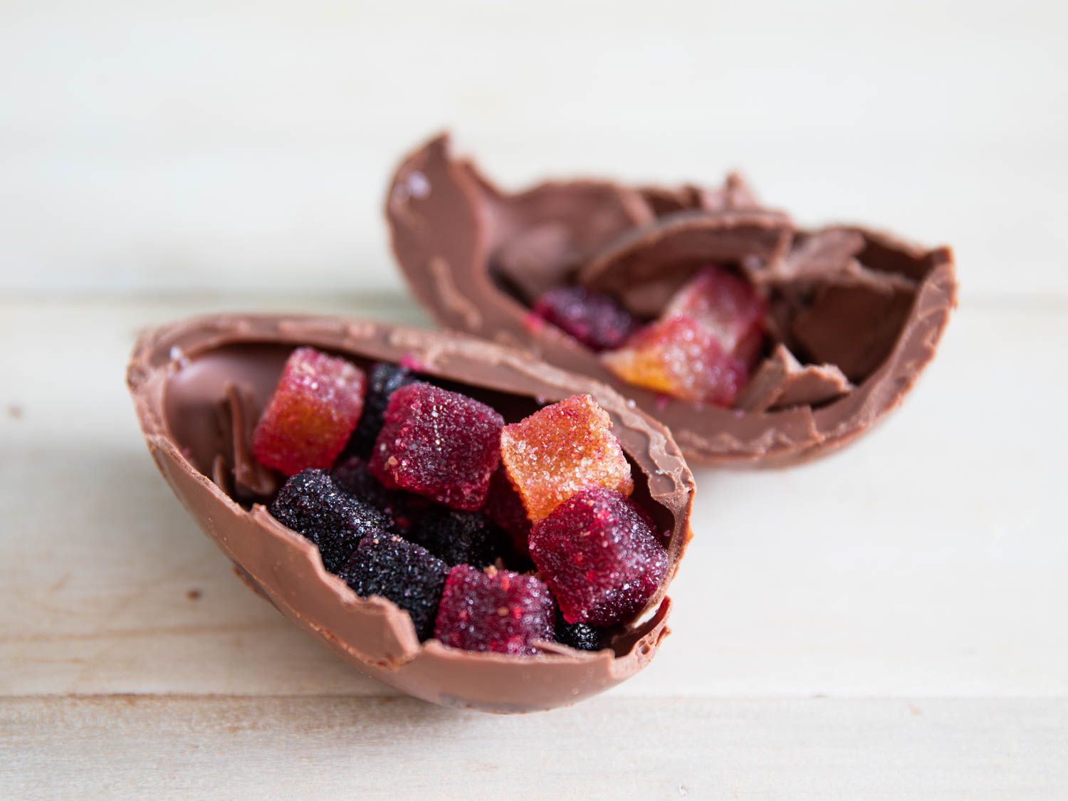 A milk chocolate Easter egg broken open, revealing the assortment of pate de fruits inside. 