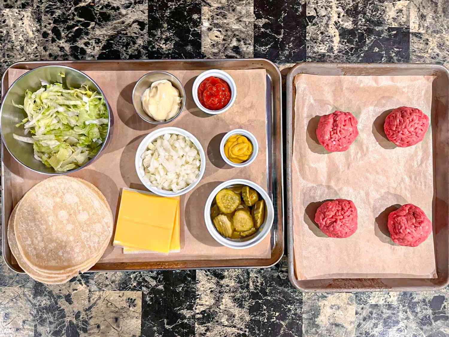 A tray with beef patties and a tray with smash burger quesadilla condiments, including cheese, onions, and flour tortillas