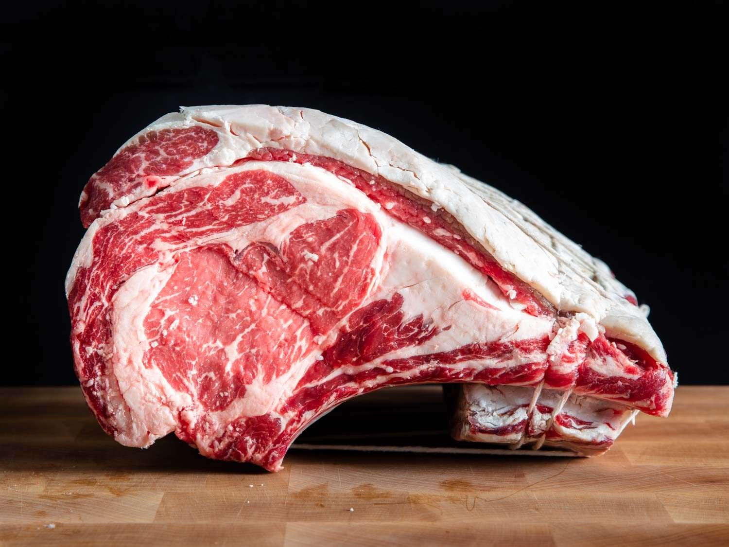 Raw prime rib roast on a cutting board.