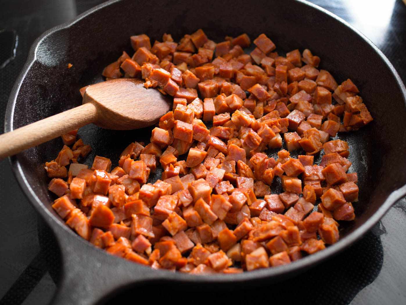 Diced Spanish chorizo being cooked in a cast iron skillet.