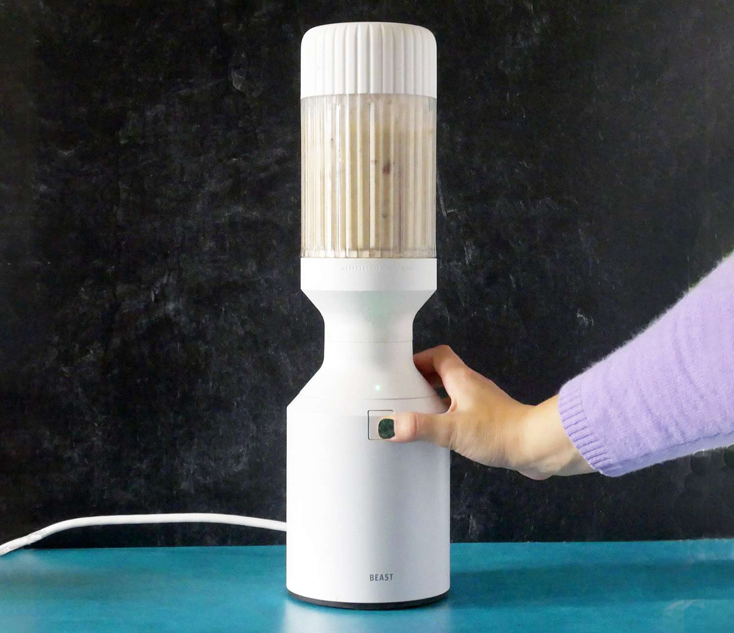 pressing the start/pulse/stop button to blend a date, banana and peanut butter smoothie