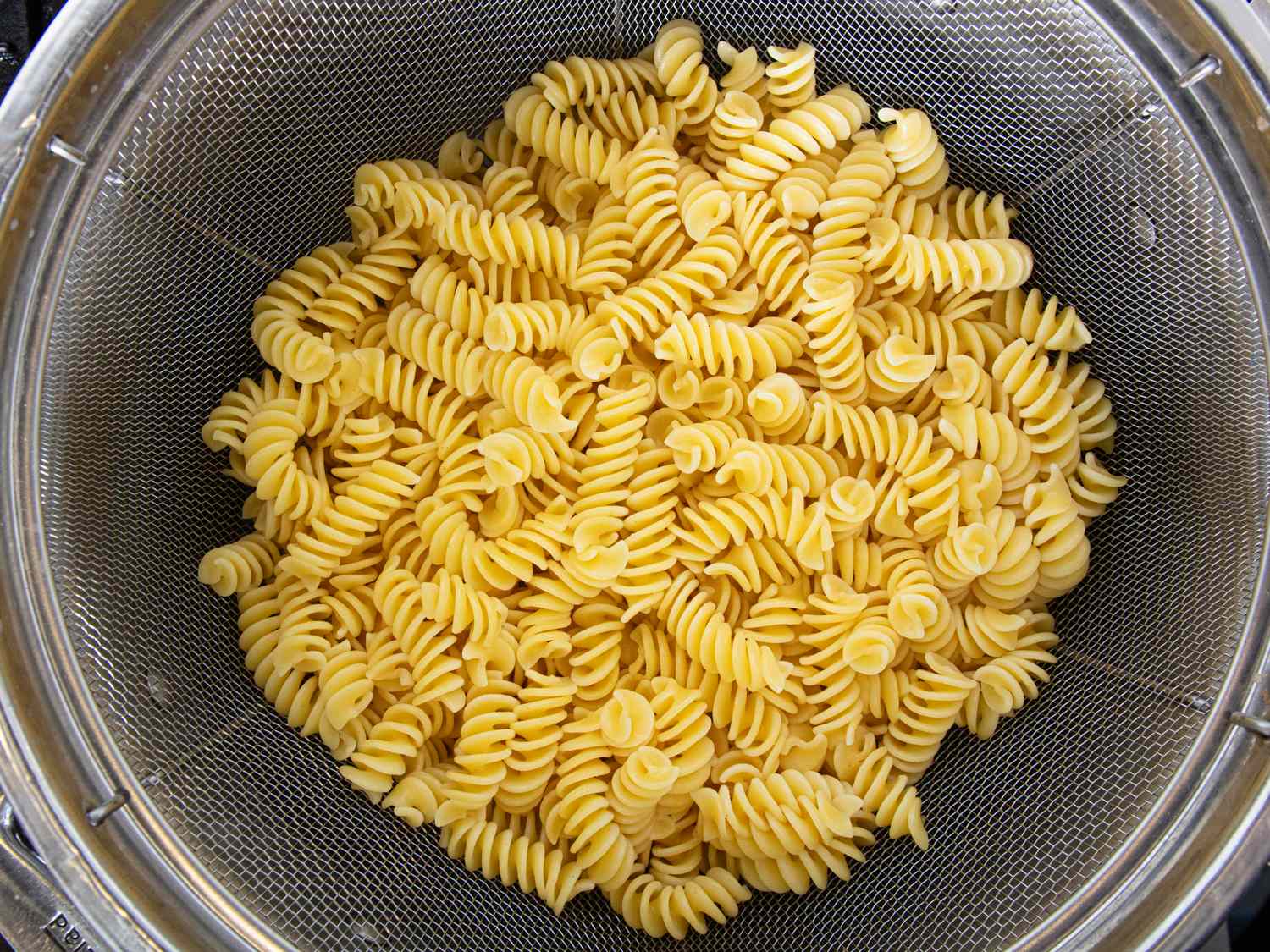 Cooked rotini pasta draining in a colander