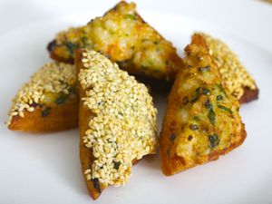 Closeup of shrimp toast triangles, served on a white plate.