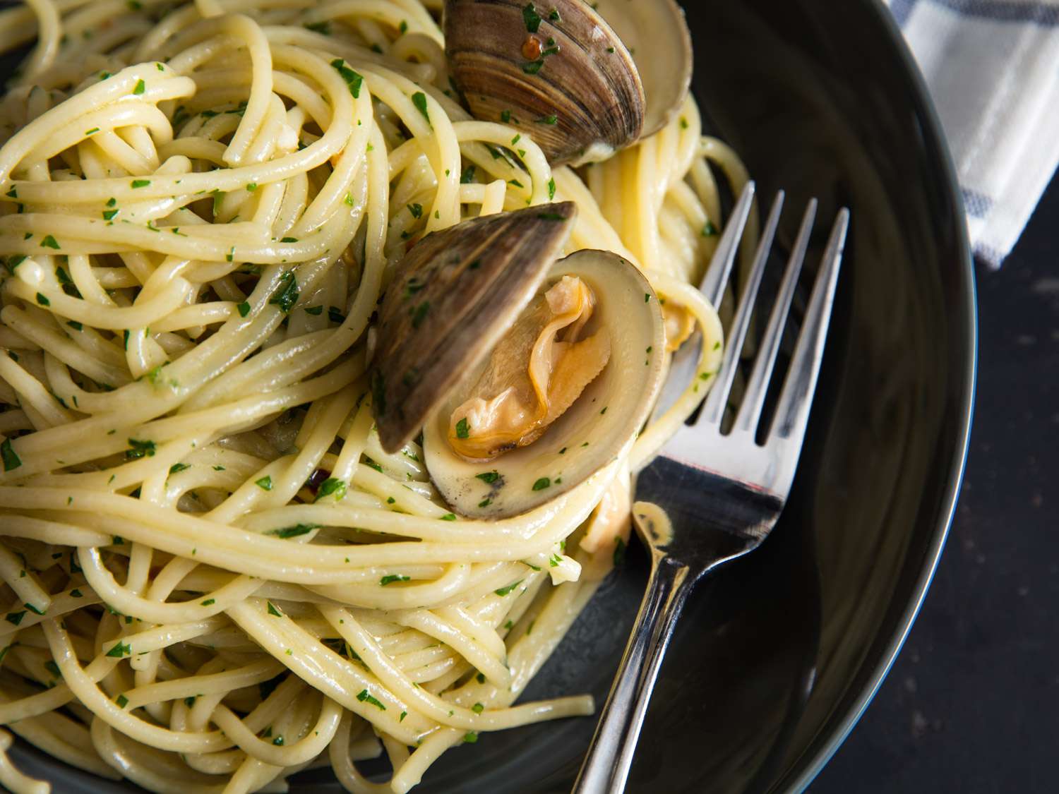 Pasta alle vongole resting in a dish with fork alongside
