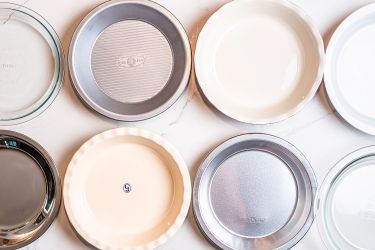 An overhead view of pie pans on a white surface