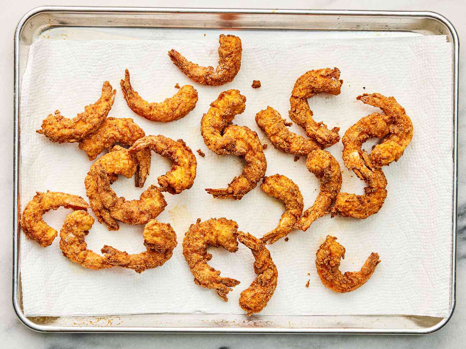 Shrimp resting on paper towel on sheetpan