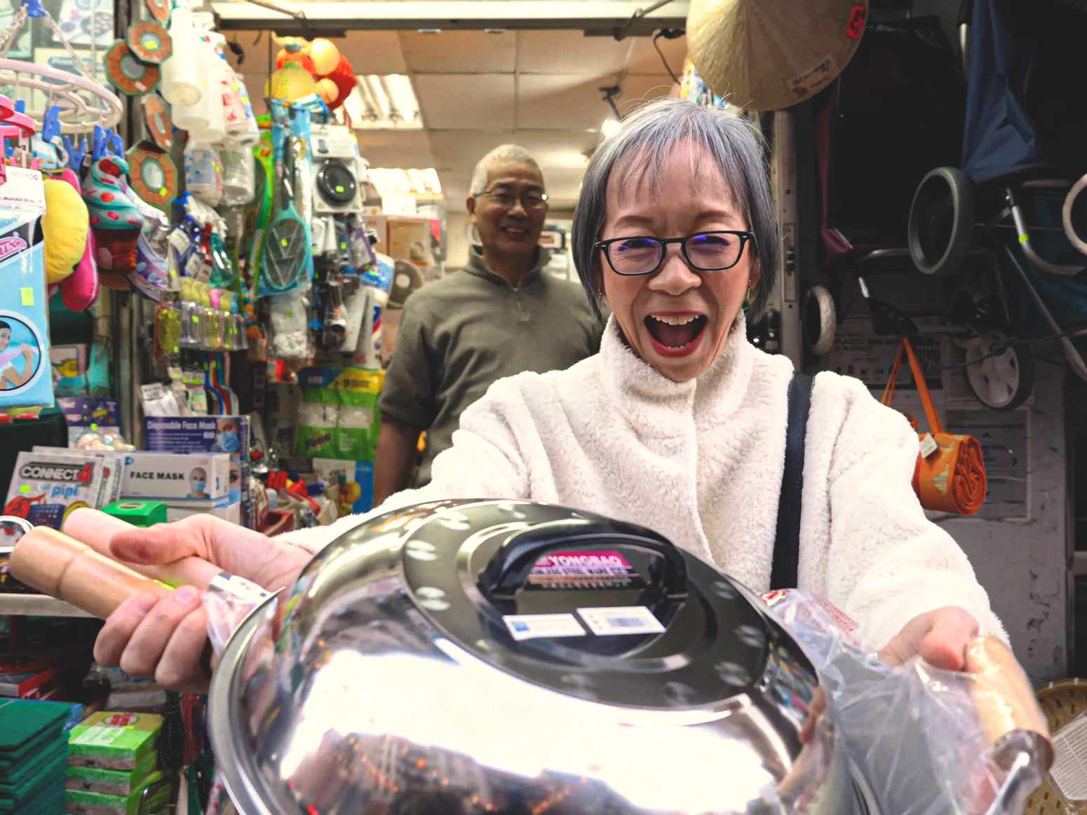 Grace Young showing a newly purchased Wok to the camera, in front of the store owner