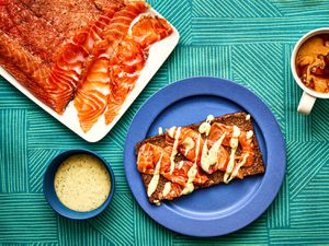 Overhead view of gravlax on pumpernickel bread with a coffee cup and sauce