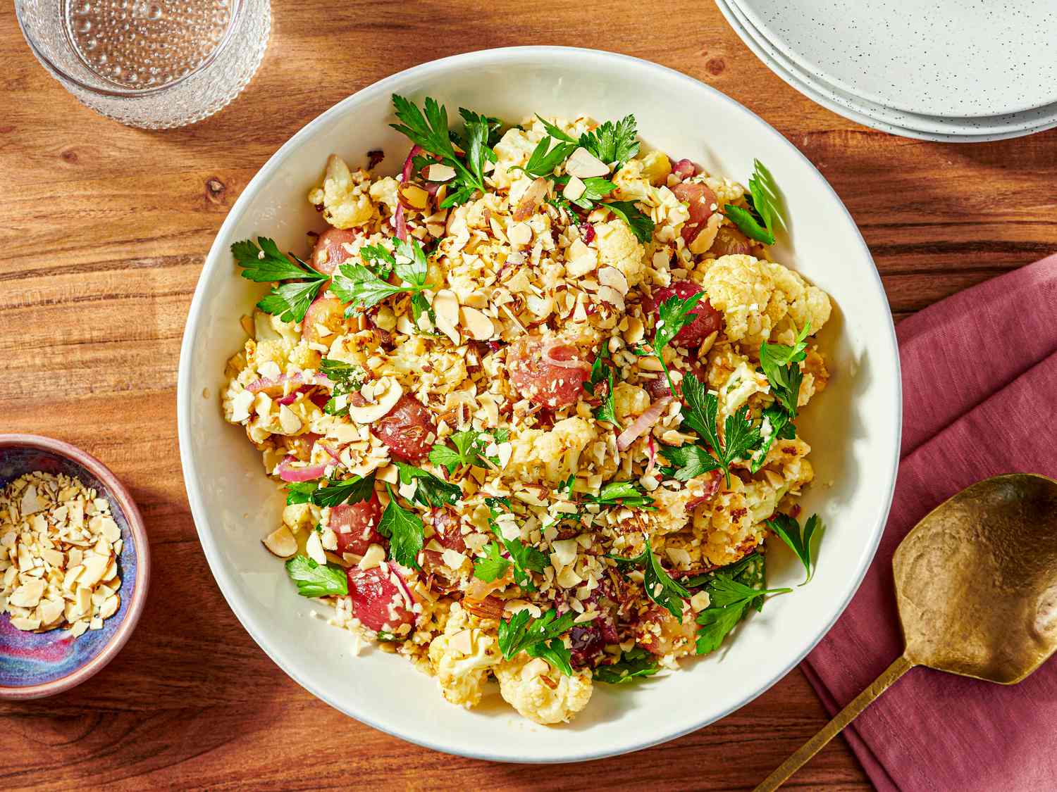 A dish of roasted cauliflower and grape salad topped with nuts and parsley