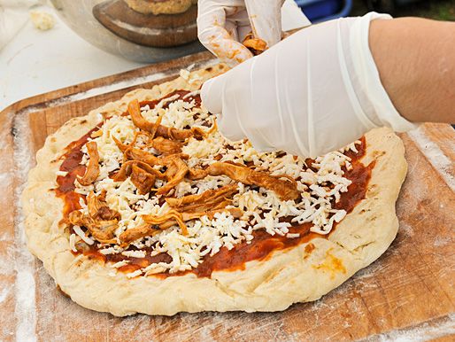 Pizza dough topped with barbecue pizza sauce and cheese is topped with pulled pork before grilling.