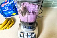 A blueberry and banana smoothie being blended in the Cuisinart Velocity Ultra 7.5 1 HP Blender on a kitchen counter