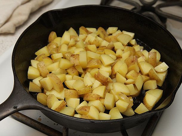 Diced potatoes cooking in a cast iron pan.