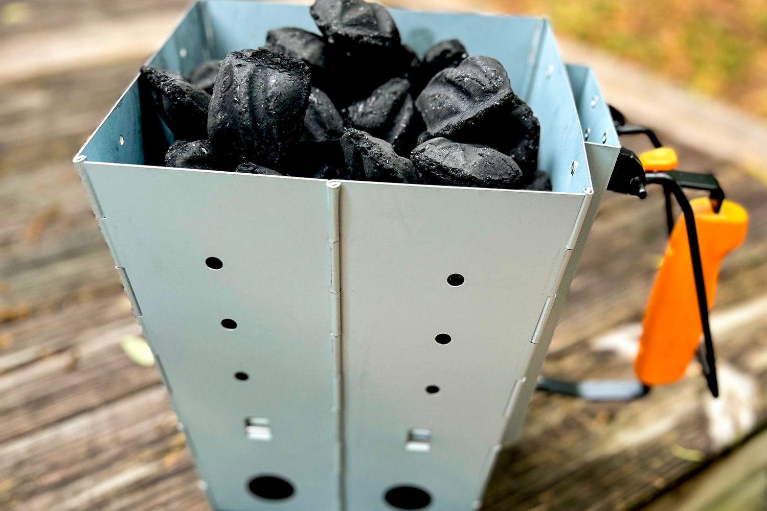a charcoal chimney starter filled with briquettes